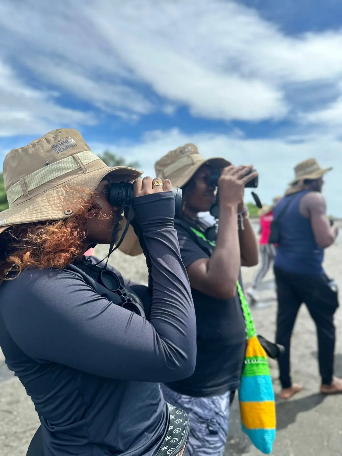 Mujeres observando aves con binóculos en la playa